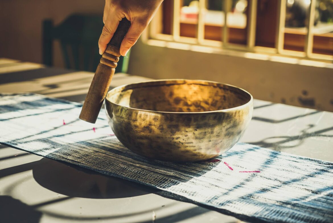 Hand met slaghout bij een klankschaal aan het begin van een mindfulness meditatie